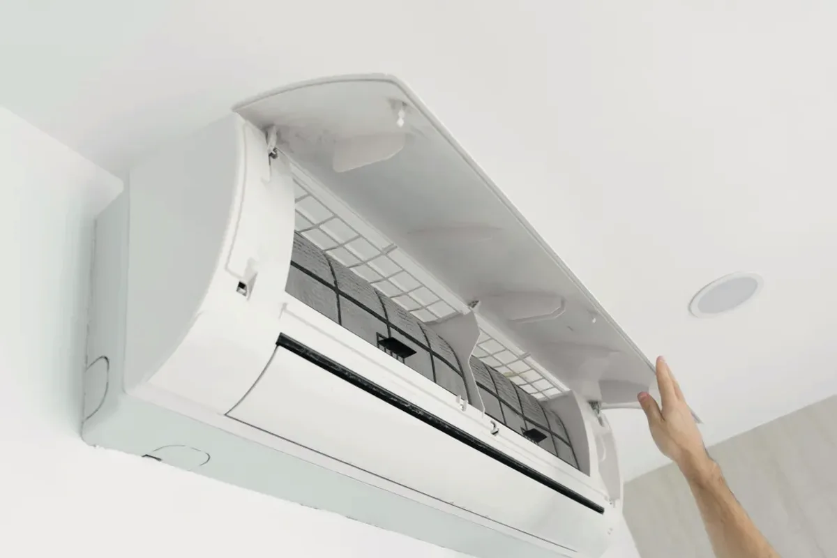 Hand opening the cover of a wall-mounted ductless air conditioner